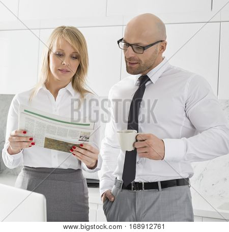 appy mid adult business couple using laptop at kitchen counter