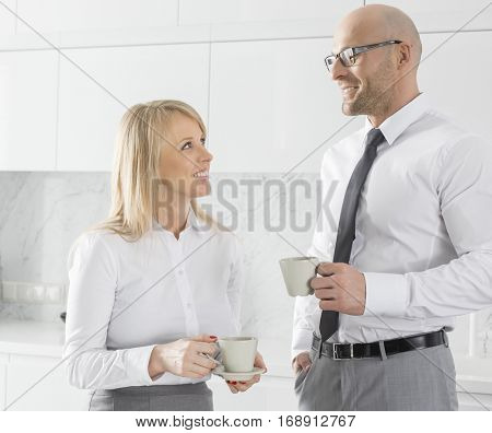 appy mid adult business couple using laptop at kitchen counter