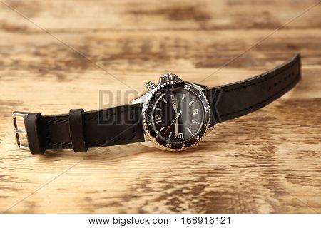 Stylish watch with leather wristlet on wooden background