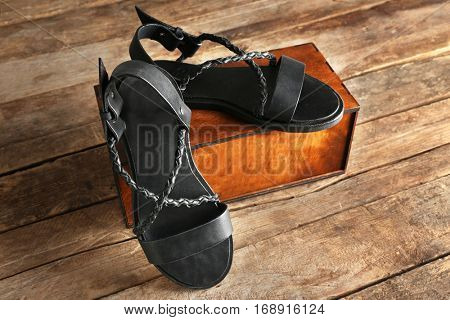New leather sandals and gift box on wooden background