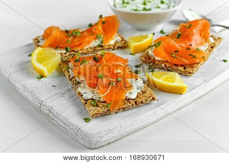 Homemade Crispbread toast with Smoked Salmon, Melted Cheese and cress salad. on white wooden board.