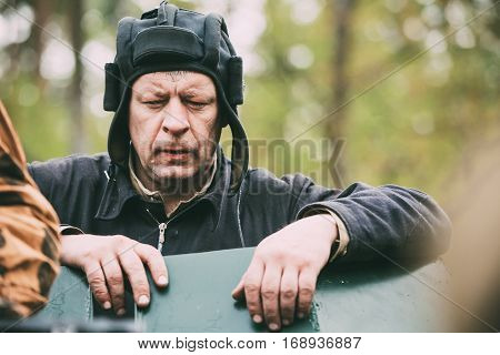 Pribor, Belarus - April 24, 2016: Close Up Portrait Of Unidentified Re-enactors Dressed As Russian Soviet Crew Member Soldier Of World War Ii Standing At Armoured Soviet Scout Car Ba-64 In Forest.