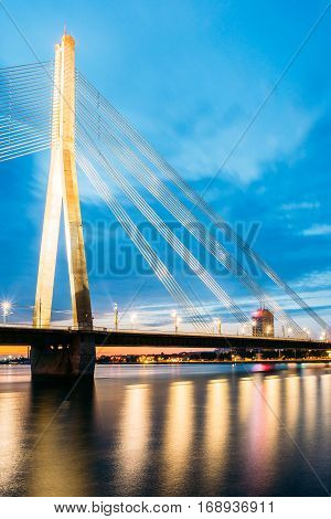Riga, Latvia. Scenic View Of  Vansu Cable-Stayed Bridge In Bright Night Illumination Over The Daugava River, Western Dvina And Color Reflexions On Water Surface.