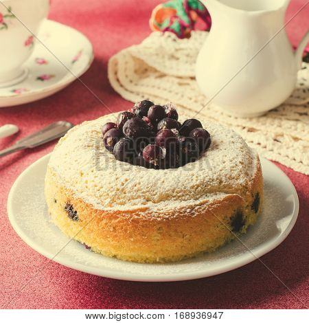 Blackcurrant cake on pink background with tea, square, toned
