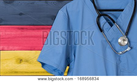 Blue doctor scrubs shirt and stethoscope hang empty in front of German flag. Illustration of medical staff coming from other countries to staff health systems