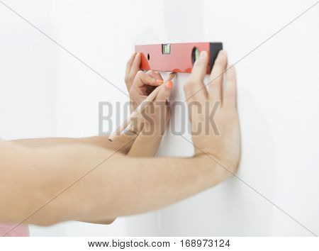 Mid-adult man marking on wall with level