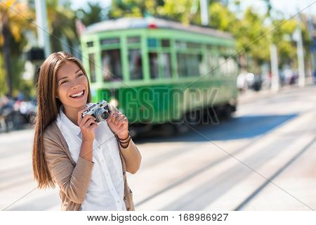 Asian woman tourist -city street lifestyle, famous tramway cable car system in San Francisco city, California during summer vacation. Travel fun taking pictures with vintage camera.