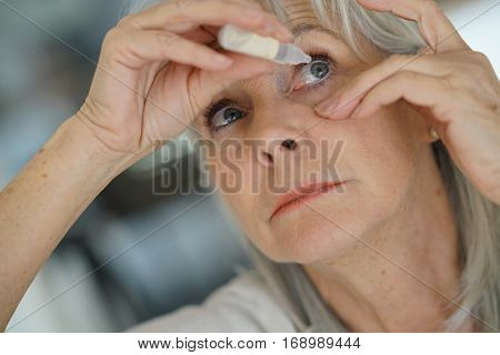 Senior woman putting eye drop 