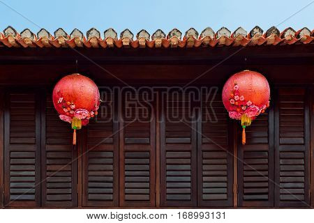 Group of traditional chinese red lanterns as decoration for China new year holidays on dark wood wall in city street. Asian arts culture travel background.