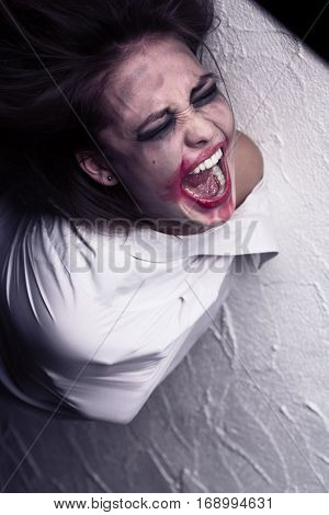 screaming crazy woman with smeared makeup in straitjacket