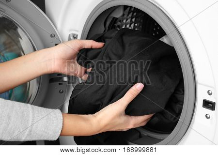 Female hands getting out clean clothes from washing machine