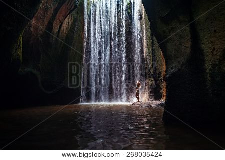 Woman Stand In Underground Cave Pool Under Falling Fresh Water Of Tukad Cepung Waterfall. Nature Day
