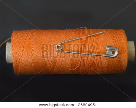 orange spolen med sikkerhedsnål isoleret på sort baggrund
