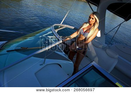 Beautiful Young Blond Woman In Swimsuit Driving Boat, Summer Holiday. Luxurious Life.