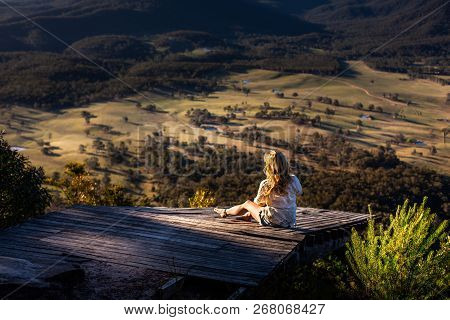 Sitting And Relaxing On The Rustic Timber Platform Jutting Out Over The Cliffs In The Warm Late Afte