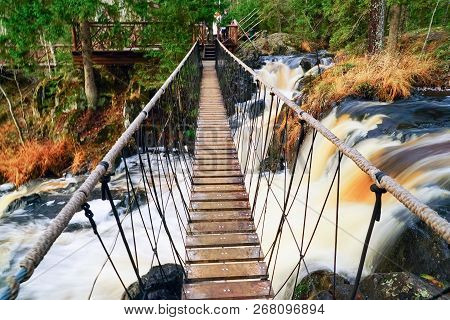 Suspended Pedestrian Bridge Over A Waterfall On The Tohmajoki River.