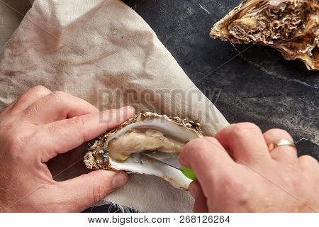 View Of Male Hands Shucking Fresh Oyster, View From Above
