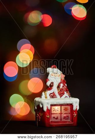 Santa Claus Statuette Doing An Exercise Waiting For Christmas. Colored Bokeh