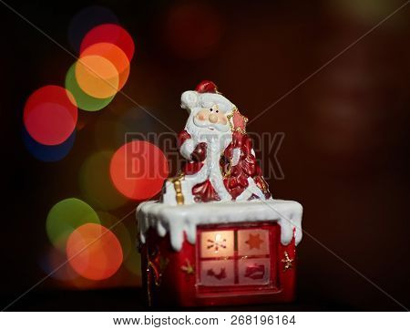 Santa Claus Statuette Doing An Exercise Waiting For Christmas. Colored Bokeh