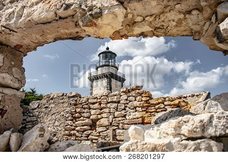 Old Retro Lighthouse Against Blue Sky Trough A Old Stone Wall With A Hole To Look At The Lighthouse