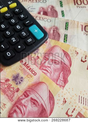 Approach To Stacked Mexican Banknotes Of 100 Pesos And Calculator