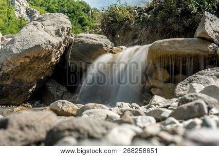 Mountain River With Rapid Stream And With Bright Blurred Waves. Big Mossy Boulders In Clear Water.