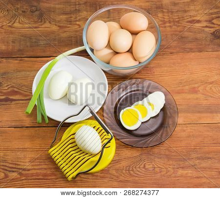 Egg Slicer With Egg In It, Partly Sliced, Peeled And Not Cleaned Boiled Eggs In Different Dishes On 