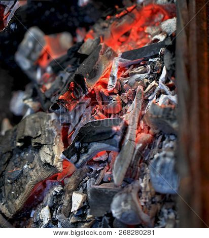 Burning Coals In The Barbecue On A Blurred Background, The Texture Of The Flame