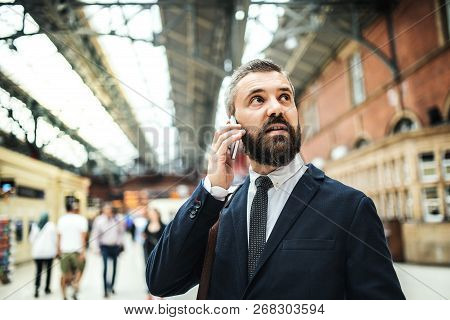 Businessman With Smartphone On The Trian Station In London, Making A Phone Call.