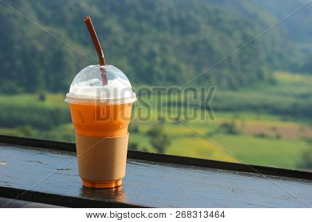 Thai Iced Tea In Plastic Cup With Natual View As Background.