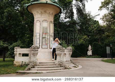 Beautiful Cuple Stand On The Stairs And Hug Each Other. Man And Woman Walking In The Park. Lovestory