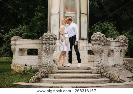Beautiful Cuple Stand On The Stairs And Hug Each Other. Man And Woman Walking In The Park. Lovestory