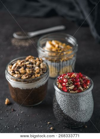 Set Of Chia Pudding In Different Glass Jars On Dark Table. Assortment Of Chia Puding With Different 