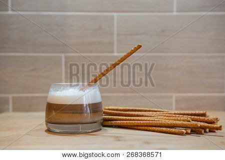 Multilayer Coffee Or Cappuccino In A Glass Cup With Bread Straw