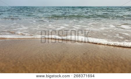 Low Angle / Ground Level Photo Of Wet Sand On The Beach, Sea In Background.