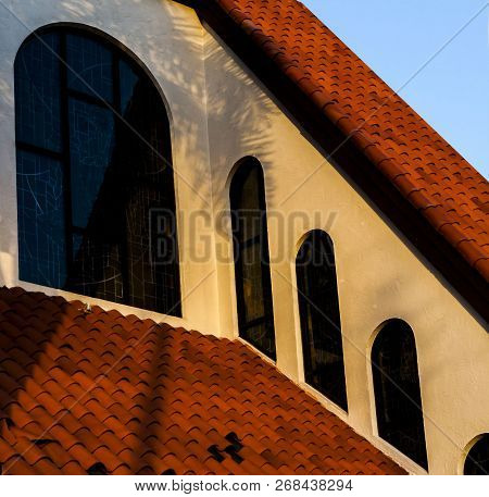 Community Catholic Church Roff Top Close Up Of The Stained Arched Windows With A Blue Sky Background