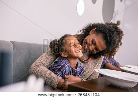 Cute Beaming Girl Smiling Broadly While Having Fun With Her Loving Mom