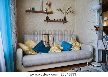 The Interior Of The Room With A Sofa And Pillows On It And Shelves Abouve It. Things On The Shelf