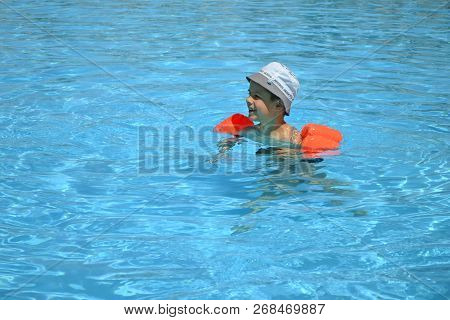 A Boy 7 Years Old Swiming And Playing In A Pool With Resque Rings