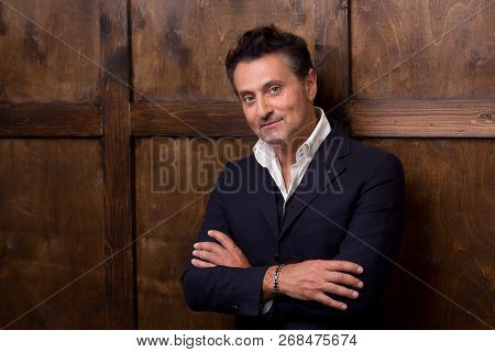 Calm Handsome Middle Aged Man In Elegant Clothes Standing Close To The Wall And Looking At You