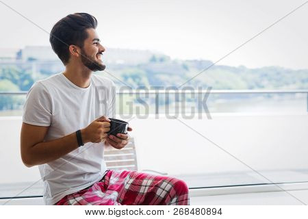 Young Man Drinking Coffee At Home In Morning
