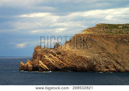 Cliffs Of Cape Na Ponca With Sunny Lights Against Dramatic Blue Sky. Fornells, Menorca, Balearic Isl