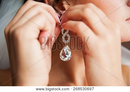 Wedding Bride Hangs Gold Earrings With Diamond.