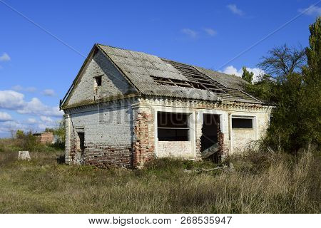An Old Abandoned Collapsing House. The Broken Roof And The Falling Brick From The Walls