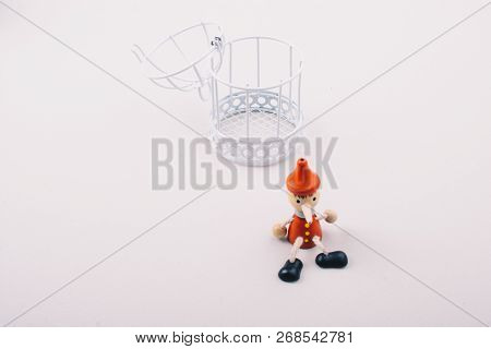 Metal Cage And Little Puppet Pinocchio Made Of Wood