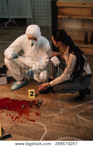 Forensic Investigator And Concentarted Female Detective Taking Notes And Investigating Crime Scene T