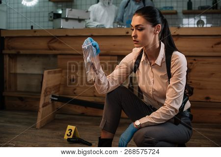 Concentarted Female Detective Collecting Evidence At Crime Scene