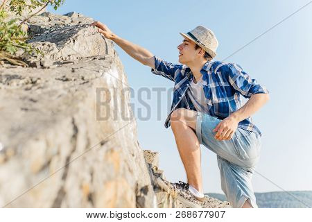 Male Hiker Climbing Up Mountain Cliff During Hiis Travel