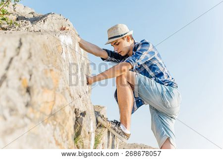 Male Hiker Climbing Up Mountain Cliff During Hiis Travel