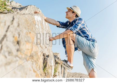 Male Hiker Climbing Up Mountain Cliff During Hiis Travel